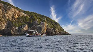 Morning Light Coastline Drucke: A boat moves along the coast with distinctive cliffs under a sky full of dramatic clouds