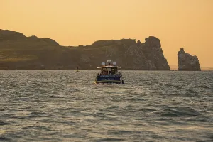 European Coastline Photography Drucke: Boat on sea in front of cliffs at sunset