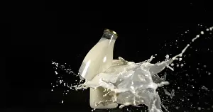 Dark Colored Background Image Drucke: Bottle of Milk Exploding against Black Background