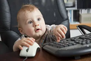 Young Boy At Desk Drucke: Boy, 10 months, using a computer mouse and keyboard