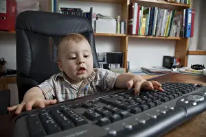 Young Boy At Desk Drucke: Boy, 10 months, using a pc keyboard