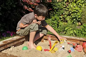 Casual Clothing For Kids Drucke: Boy, 7 years, playing in sandpit
