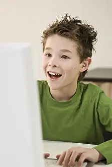 Young Boy Smile Drucke: Boy laughing, sitting in front of his computer