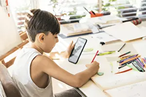 Online Education Drucke: A boy is learning to draw with her smart phone