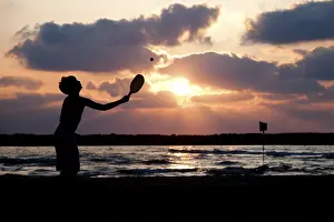 Dramatic Evening Sky Photo Drucke: Boy playing with bat and ball on the beach