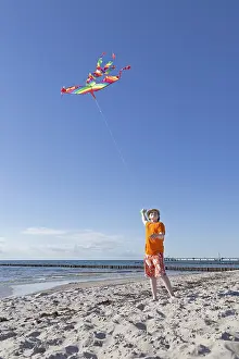 Seaside Resort In Germany Drucke: Boy playing with a kite on the beach