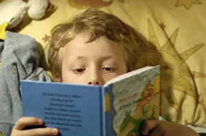 Boy Reading In Bed Drucke: Boy reading in bed