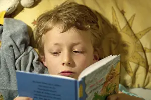 Boy Reading In Bed Drucke: Boy reading in bed