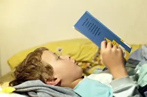 Boy Reading In Bed Drucke: Boy reading in bed