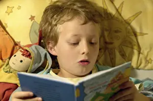 Boy Reading In Bed Drucke: Boy reading in bed