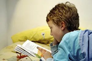 Boy Reading In Bed Drucke: Boy reading in bed