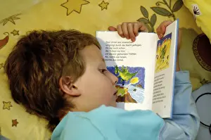Boy Reading In Bed Drucke: Boy reading in bed