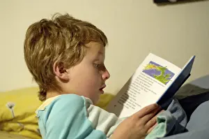 Boy Reading In Bed Drucke: Boy reading in bed