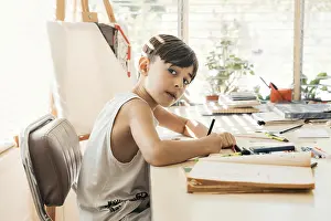 Boy Looking At Camera Drucke: Boy sitting in his drawing class