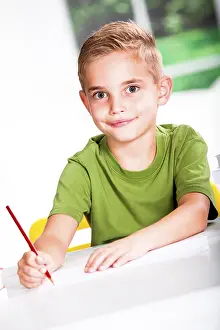 Caucasian Boy Smiling Drucke: Boy with a sketch-pad at a table