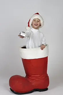 Studio Shot Of Child Drucke: Boy with small gift in a Christmas boot