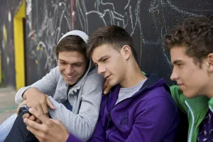 Leisure Activities Drucke: Three boys sitting with their backs against a wall