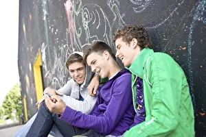 Caucasian Ethnicity Drucke: Three boys sitting with their backs against a wall