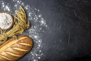 Top Down View Of Baked Goods Drucke: Bread with flour and wheat on black stony table