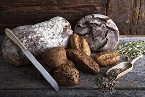 Rustic Wooden Surface Drucke: Bread loaves, rolls and a bread knife