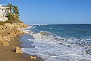 Steep Cliff Overlooking The Sea Drucke: Breaking waves on a sandy beach with a view rocks