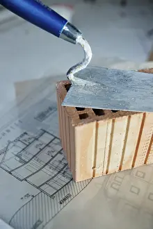 Home Construction Plan Drucke: Brick trowl and brick on a construction plan