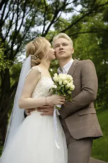 Happy Couple In Park Drucke: A bride and groom pose lovingly in a park