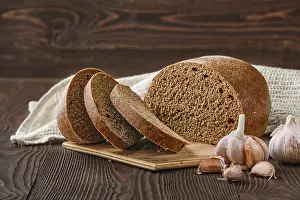 Gourmet Bakery Products Drucke: Brown garlic bread on cutting board on the table