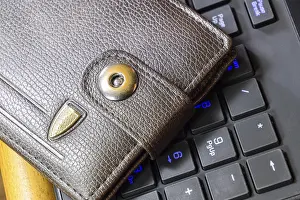 Drucke von Brauner Brieftasche liegt auf einer schwarzen Computer-Tastatur. Atyrau, Kasachstan Verwandte Bilder Drucke: Ein brauner Geldbeutel liegt auf einer schwarzen Computer-Tastatur.