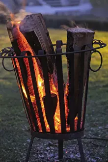 European Evening Sky Drucke: Burning logs in a fire basket create a warm