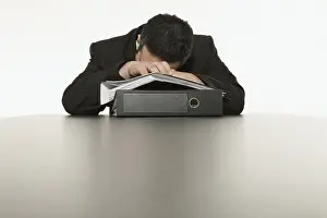 Tired Businessperson Drucke: Businessman sleeping, his head laying on a stack of files