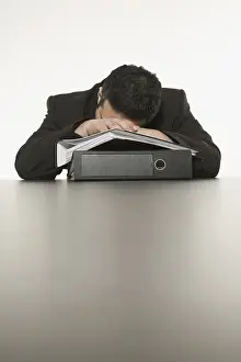 Tired Businessman Drucke: Businessman sleeping, his head laying on a stack of files