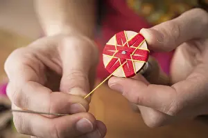Handicraft Tool Drucke: Button maker stitching and wrapping red and yellow yarn into star pattern