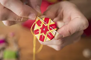 Handicraft Tool Drucke: Button maker stitching and wrapping red and yellow yarn into star pattern
