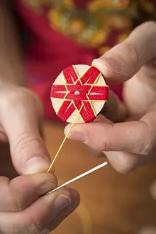 Traditional Bavarian Crafts Drucke: Button maker stitching and wrapping red and yellow yarn into star pattern