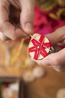 Regional Handicrafts Drucke: Button maker stitching and wrapping red and yellow yarn into star pattern
