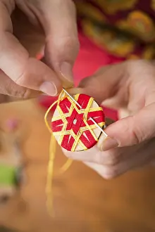 Regional Handicrafts Germany Drucke: Button maker stitching and wrapping red and yellow yarn into star pattern