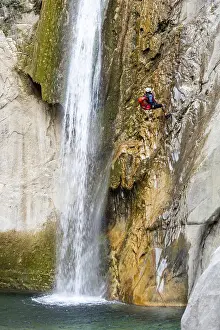 Waterfall Adventure Drucke: A canyoneer rappels down steep cliffs next to a waterfall