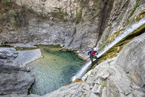 Adventure Travel Drucke: A canyoneer rappels down steep cliffs next to a waterfall