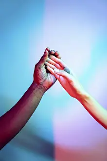 Vibrant Background Image Drucke: A captivating image of two multiethnic hands touching against a vibrant background