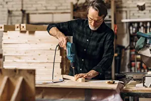 Senior Man Working Drucke: Carpenter using electric drill