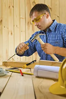 Construction Worker Drucke: Carpenter works with the chisel