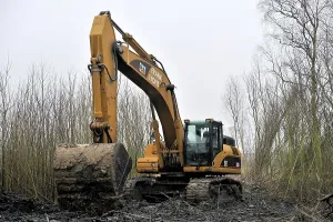 A large digger in the process of attempting to pull another smaller digger out of the mud