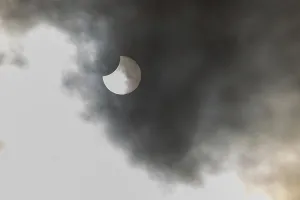 European Nature Phenomenon Drucke: A partial solar eclipse occurs when the moon eclipses part of the sun and is surrounded by dynamic cloud formations