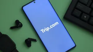 Mobile Phone Technology Drucke: Trip.com logo visible on a smartphone surrounded by a tech setup