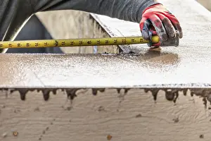 Pool Coping Installation Drucke: Cement construction worker using measuring tape while forming pool coping