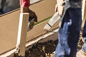 Construction Site Laborer Drucke: Cement construction worker using measuring tape while forming pool coping