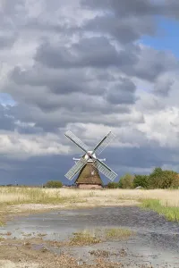 Dutch Countryside Scene Drucke: Charming Dutch windmill by river in sunlight