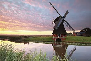 European Historic Landmark Drucke: Charming windmill by river at dramatic sunrise