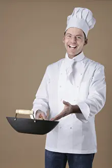 Studio Shot Of A Chef Drucke: Chef gesturing toward a wok in his hand